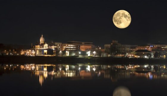 Nightime in Fredericton New Brunswick with full moon and lights reflecting off the water of the Saint John River, Canada