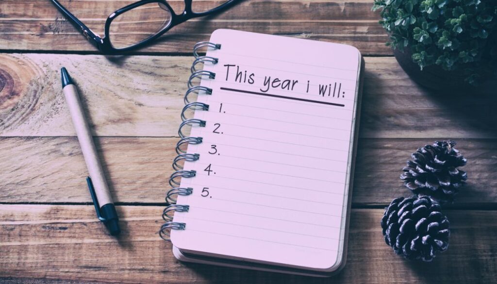 New Year Resolutions List on Notepad on Top of Wood Desk