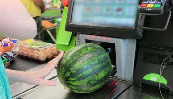 Girl scanning shopping (watermelon) at self-service supermarket checkout till (self-checkout)