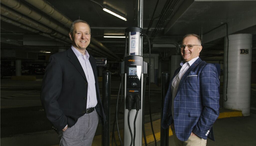 (From left), Ryan Mitchell, President and CEO of Saint John Energy, is joined by Wayne Long, MP for Saint John-Rothesay, with a new Level 2 electric vehicle charger installed in the Market Square parking garage in Saint John. (Photo Courtesy: Saint John Energy)