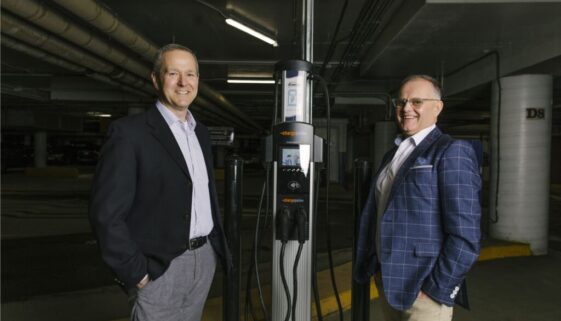 (From left), Ryan Mitchell, President and CEO of Saint John Energy, is joined by Wayne Long, MP for Saint John-Rothesay, with a new Level 2 electric vehicle charger installed in the Market Square parking garage in Saint John. (Photo Courtesy: Saint John Energy)